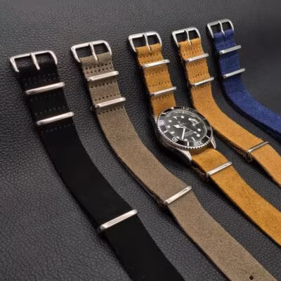 Multiple color options of Soft Suede NATO Straps displayed on Rolex Submariner wristwatch, showcasing navy blue, brown, grey, khaki, and black colors.