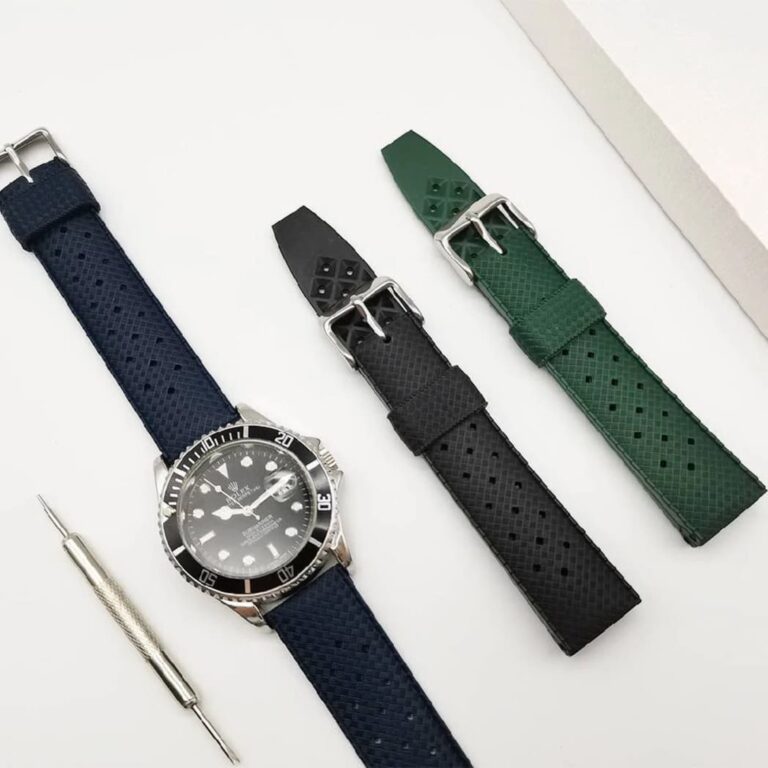 Set of tropical fluororubber watch straps in black, blue, and green paired with a luxury Rolex Submariner dive watch.