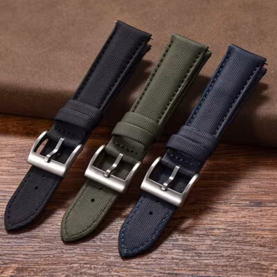 A close-up view of the buckle ends of the black, green, and blue quick-release leather sailcloth watch straps.