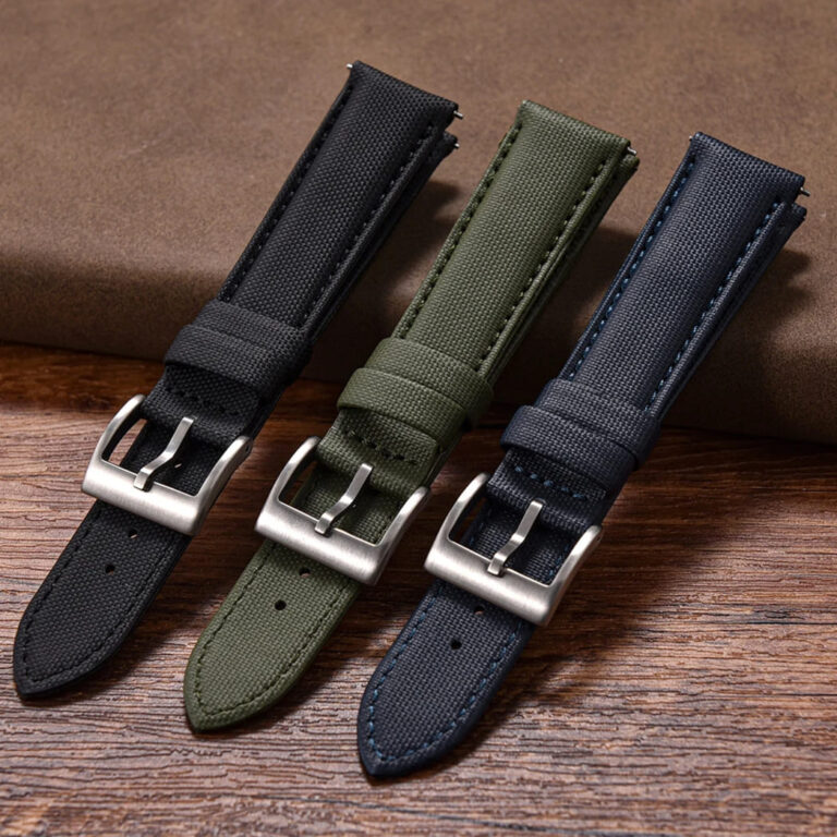 A close-up view of the buckle ends of the black, green, and blue quick-release leather sailcloth watch straps.