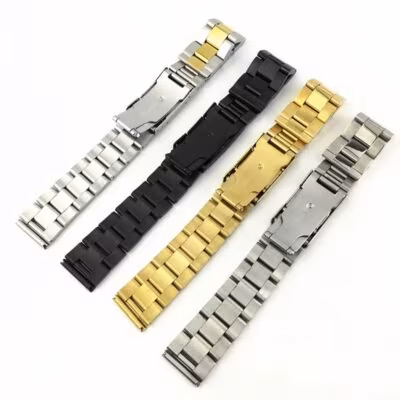 Underside view of four oyster-style stainless steel watch straps in silver, black, gold, and two-tone, showing the quality of the engraved clasps.